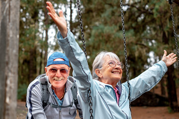 Obraz premium Happy senior couple in mountain picnic area enjoying with swing like children, enjoying healthy lifestyle in nature
