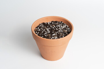 Terracotta pot with porous soil mixture in isolated white background.