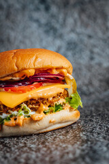 Fresh and juicy double beef cheeseburger with melted cheese on dark textured background