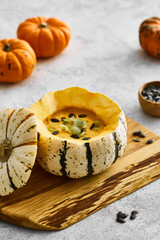 Pumpkin cream soup served in a squash with seeds