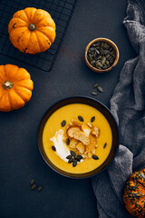 Pumpkin cream soup with croutons on dark background