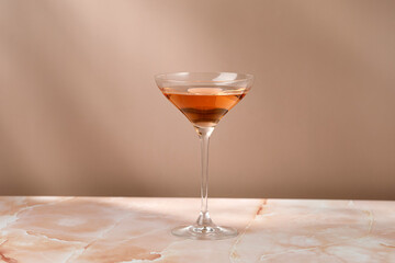 Glass with wine rose on beige marble background with shadows on the wall. Copy space, place for text.