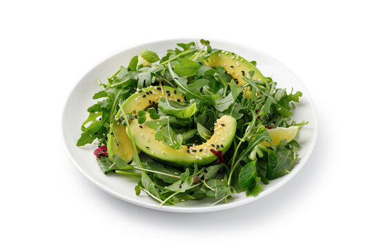 Green vegan salad with avocado and mix lettuce, arugula on white plate isolated on a white background with clipping path, cut out.