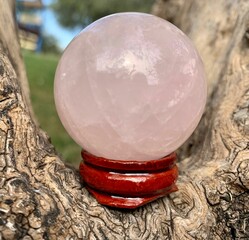 Closeup shot of the pink quartz ball on a tree