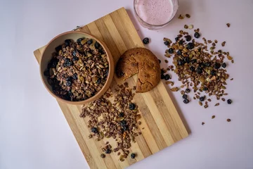 Fotobehang Top view of a bowl of homemade nut and choco granola with a chocolate cookie on a wooden board © Oksana Taran/Wirestock Creators