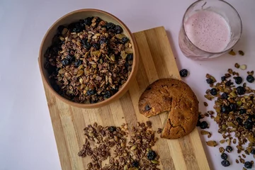  Top view of a bowl of homemade nut and choco granola with a chocolate cookie on a wooden board © Oksana Taran/Wirestock Creators