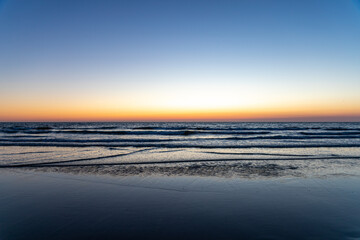 Sundown at the Dutch coastline between Noordwijk and Zandvoort. On the clear bright yellow and...