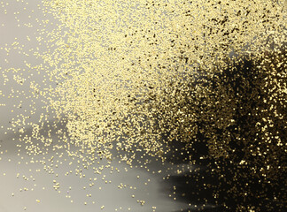 Gold (bronze) glitter shine dots confetti on black. Abstract light blink sparkle backgound.