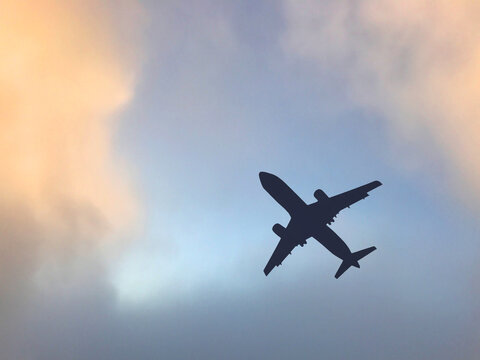 Silhouette of a passenger jet clambing after take off againsg a colourful clody sky. No people. Copy space.