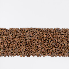 Coffee beans laid out in one wide row on a white background, place for inscription and advertising.