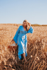 Naklejka na ściany i meble Spectacular charming blonde in a sky blue long light dress among dry grass in a field in the harvest season - rural landscape