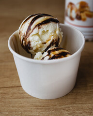 Plombir dessert - white balls of ice cream with chocolate and caramel topping in a glass
