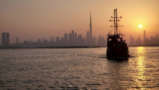 Dhow Cruise boat sailing during sunset with Dubai skyline view on background