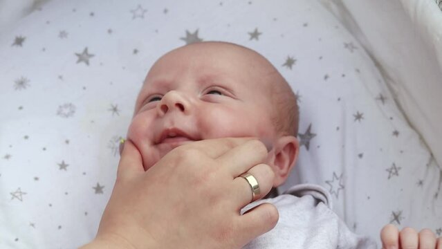 1080p slow motion footage video. Close up newborn baby child lying in baby carriage stroller buggy having fun playing, looking at her mother, smiling infant. Outside walking in pushchair, fresh air

