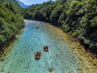 Soca Valley, Slovenia - Aerial view of the emerald alpine river Soca with rafting boats going down the river on a bright sunny summer day with green foliage. Whitewater rafting in Slovenia