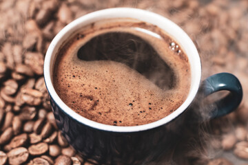 A cup of coffee and coffee beans on a black background, an aromatic and energy drink.