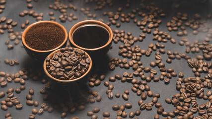 Cups of coffee and roasted coffee beans on a black background in a pair.