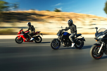 Three supersport race motorcycle riders going fast side by side on the highway with motion blur.