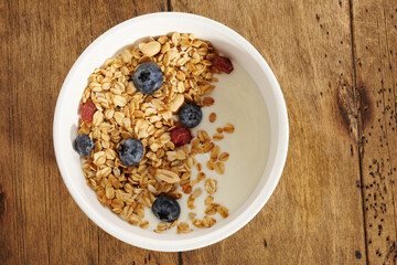 granola with yogurt and berries in a white bowl on a wooden table
