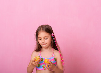 Obraz na płótnie Canvas Caucasian beautiful little girl with fresh yellow lemons on a pink background.
