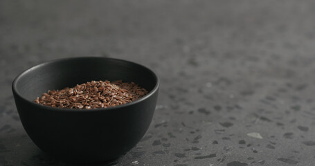 flaxseed in black bowl on terrazzo countertop with copy space