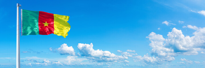 Cameroon, flag waving on a blue sky in beautiful clouds - Horizontal banner