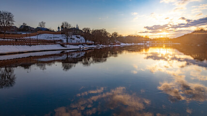 Winter landscape with river and trees at sunset.
