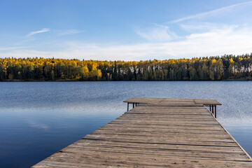Obraz premium Wooden deck near the water. Sunny autumn day near the pond.