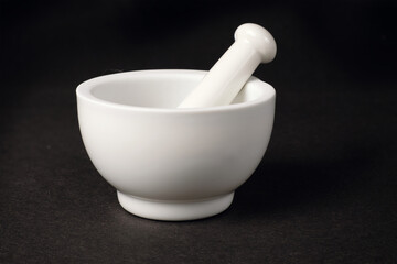 White porcelain mortar and pestle on dark surface