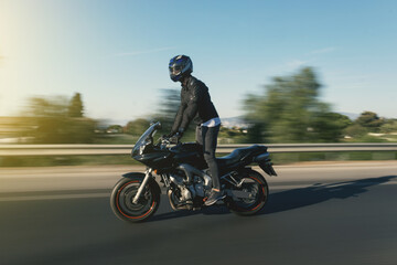 Obraz na płótnie Canvas Side view of a motorcycle rider riding race motorcycle on foot on the highway with motion blur.