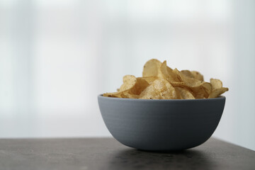 Organic potato chips with black pepper in blue bowl on counterttop