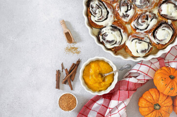Homemade Pumpkin cinnamon rolls with cream cheese in a baking dish, flat lay, top veiw. Seasonal autumn homemade pastry - cinnabons for breakfast or holidays. top view, copy space