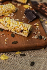 Fototapeta premium Bar with granola, dried fruits and nuts on a wooden board with dried fruits, nuts, chocolate and cereals