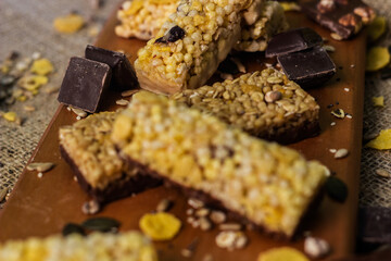 Bar with granola, dried fruits and nuts on a wooden board with dried fruits, nuts, chocolate and cereals