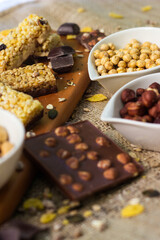 Bar with granola, dried fruits and nuts on a wooden board with dried fruits, nuts, chocolate and cereals