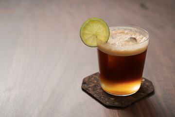 Espresso tonic in simple glass on walnut wood table with copy space