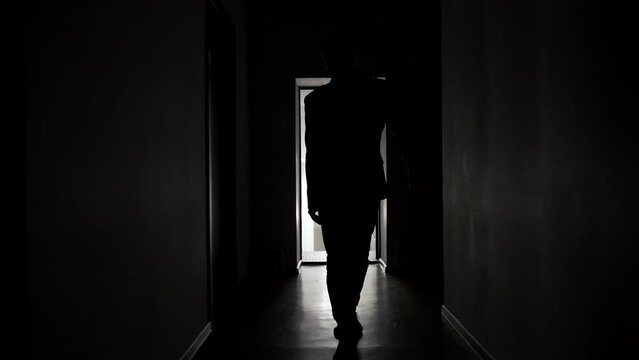 Slow motion, a man walks along the corridor of an office or hotel. backlight, a mysterious silhouette goes to the camera. High quality FullHD footage