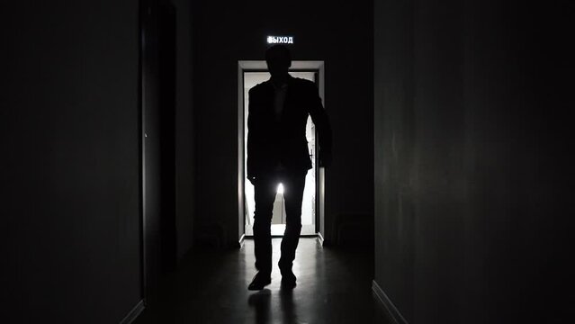 Slow motion, a mystery man walks along the corridor of an office or hotel. backlight, a mysterious silhouette goes to the camera. High quality FullHD footage