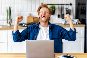 Portrait of excited young caucasian man celebrating success. Young man reading good news using...