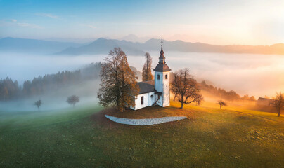 Aerial drone view of small beautiful church on a mountain in Slovenia at dawn. Beautiful autumn...