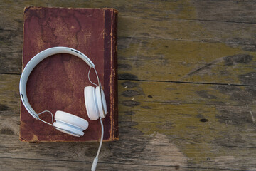 headphones on old book and wooden background