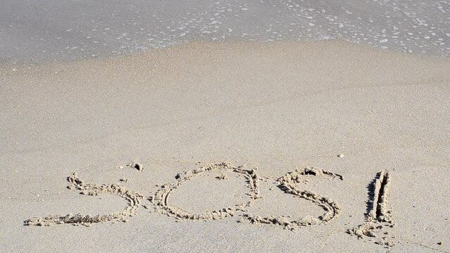SOS sign is washed off by a wave. A cry for help on