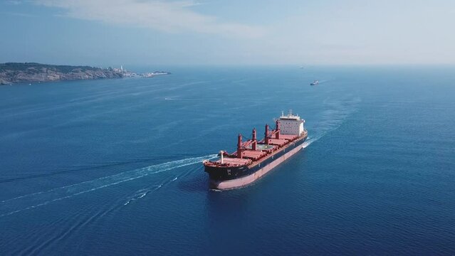 A cargo ship sailing northbound on Straits Bosporus. Aerial. Bulk carrier or bulker is a merchant ship specially designed to transport unpackaged bulk cargo, such as grains, ore, coal or timber
