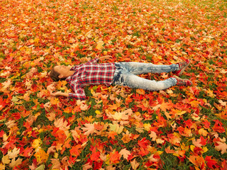 woman lies comfortably on the autumn leaves with closed eyes