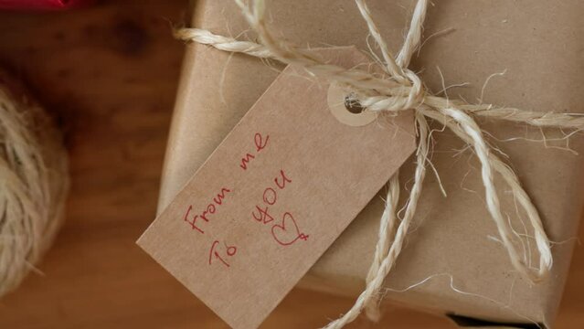Close up gift tag with text FROM ME TO YOU on eco friendly wrapped gift box.