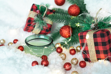 Decor of green shiny Christmas balls, lights of a Christmas garland on a white fluffy soft background. Cozy holidays. New Year holidays 2023. Place for text. Postcard for the New Year and Christmas.