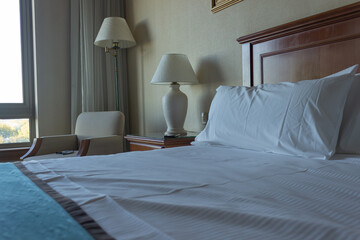 Hotel room with lamps , a chair and pillows on the bed.