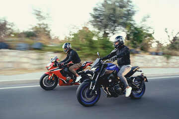 Two supersport race motorcycle riders going fast side by side on the highway with motion blur.