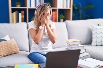 Young blonde woman studying using computer laptop at home rubbing eyes for fatigue and headache,...
