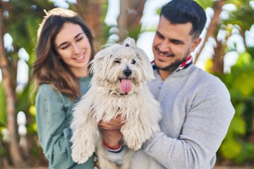 Man and woman holding dog standing together at park